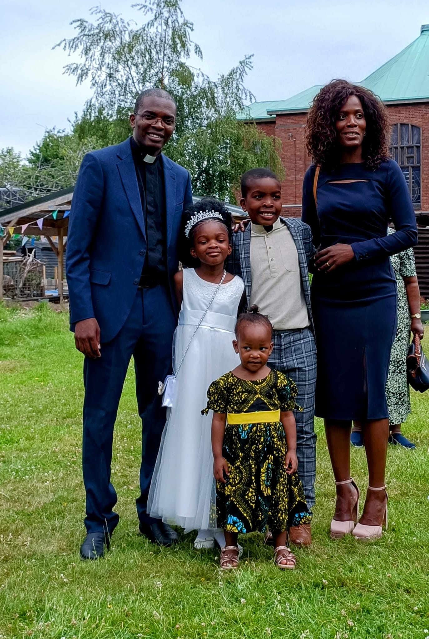 Deacon Davie, in his clerical collar, is joined by his wife and children, including his daughter wearing her First holy Communion Dress