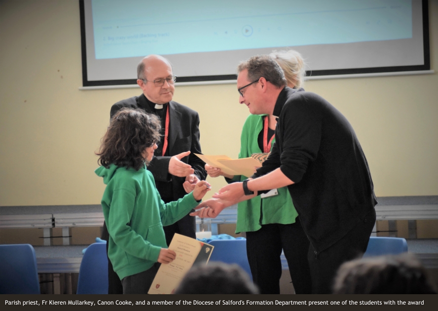 Parish priest, Fr Kieren Mullarkey, Canon Cooke, and a member of the Diocese of Salford's Formation Department present one of the students with the award